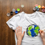 Drawing earth globe on t-shirt. Bright colours. Top view, wooden background